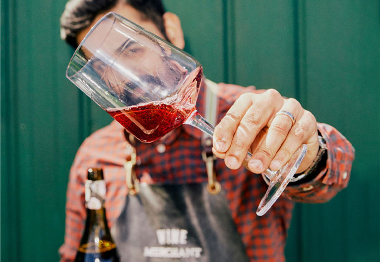 Wine expert at Dan Murphy's holding up a wine glass.