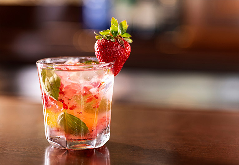 Fruity mixed drink on a table with a strawberry garnish.