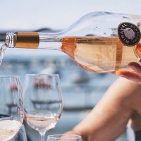 Person pours Miraval Rosé Wine into glasses near the sea.