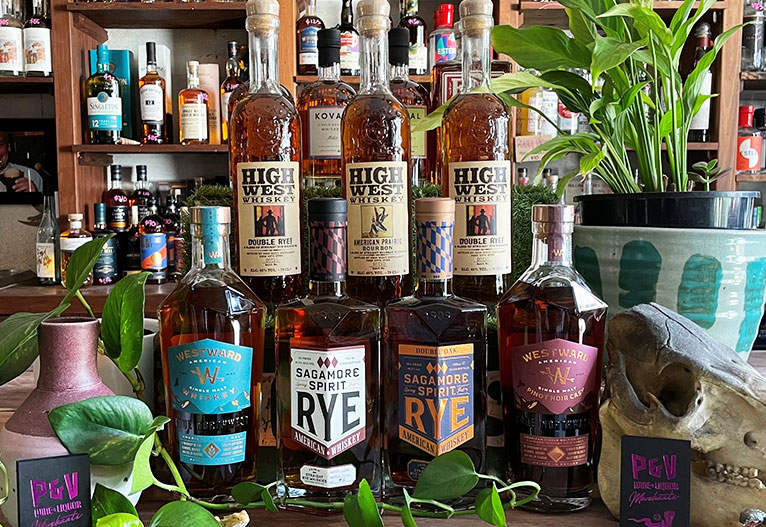 Assorted American whiskey bottles on a bench.