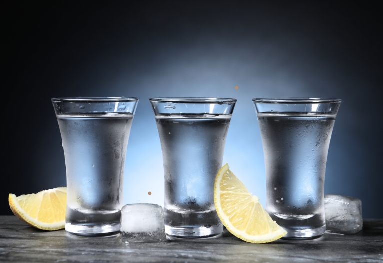 Three shot glasses filled with vodka.