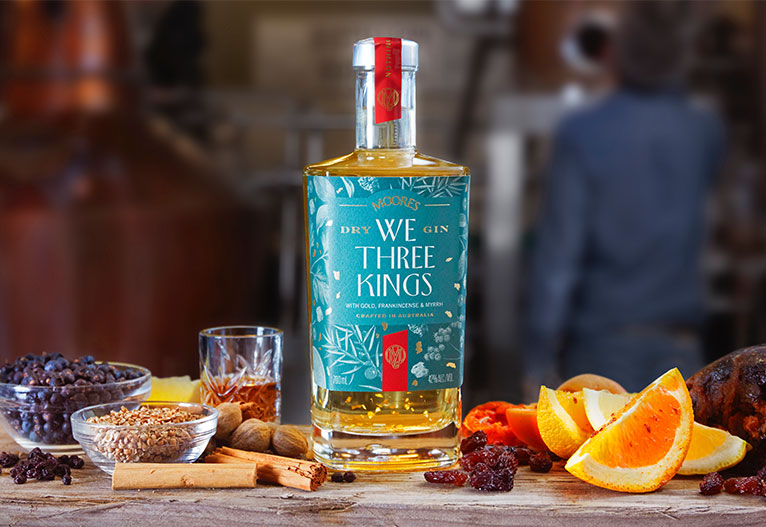 We Three Kings gin bottle on a bench with an orange wedge.