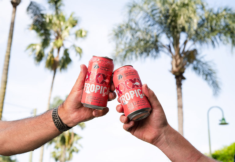 People saying cheers with XXXX Tropical Lager cans.