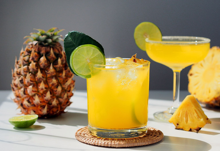 Pineapple-flavoured mixed drink with a fresh lime garnish.