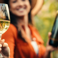 Woman holding a glass of wine and a bottle.