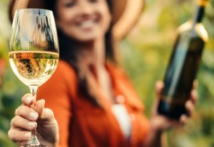 Woman holding a glass of wine and a bottle.