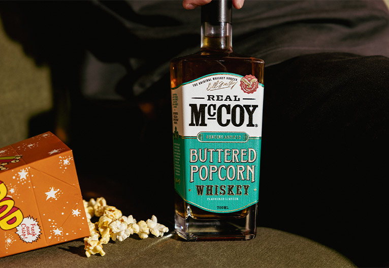 Real McCoy Buttered Popcorn Whiskey bottle on a sofa.