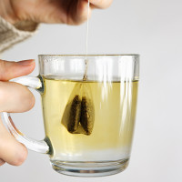 Person holding a mug of tea with a tea bag.