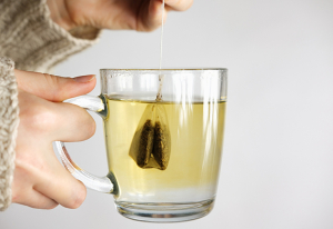 Person holding a mug of tea with a tea bag.
