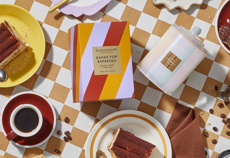 Glasshouse Eager for Espresso candle on a table of party food.