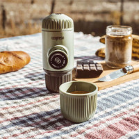 Wacaco Nanopresso manual coffee maker in green on a picnic rug.