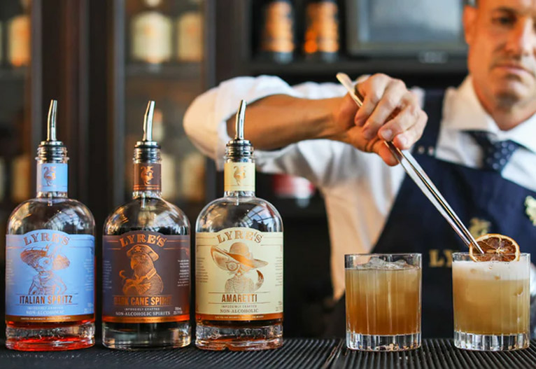 Barman making mixed drinks at a bar with Lyres non-alcoholic spirits.