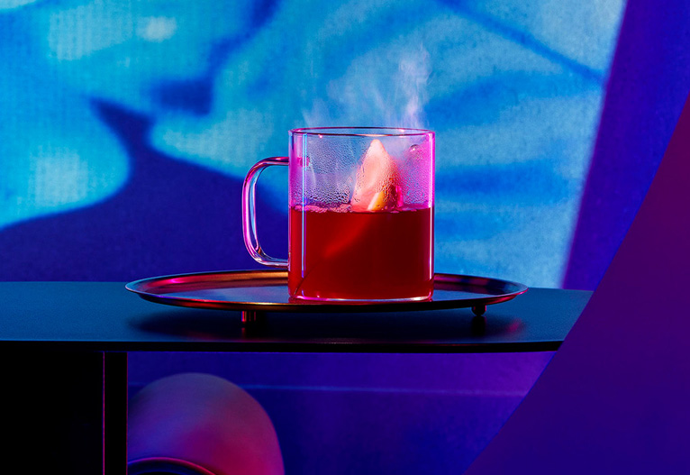 Hot toddy cocktail on a bench amidst blue light.