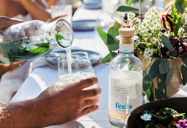 Person pouring cocktail into a glass at an outside table.