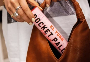 Person putting El Toro Paloma Pocket Cocktail into a handbag.