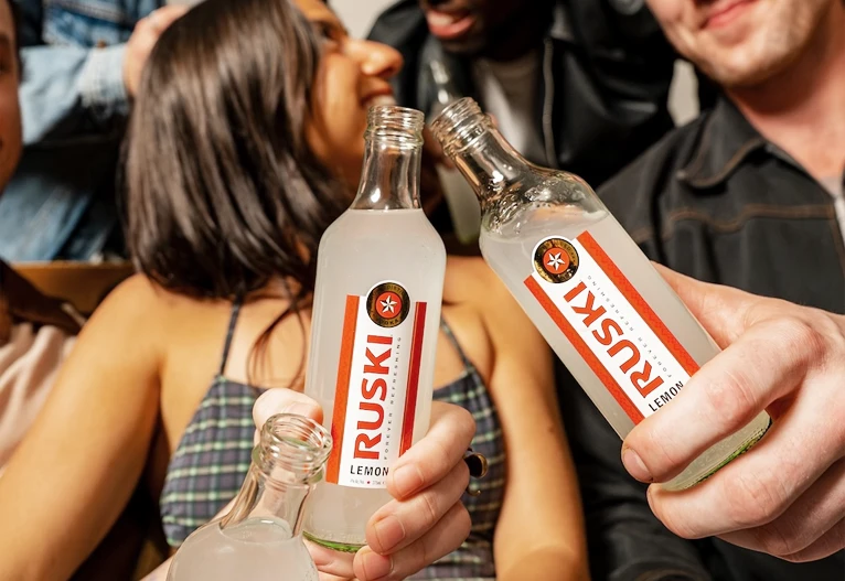 People at a party holding Ruski Lemon RTD in bottles.
