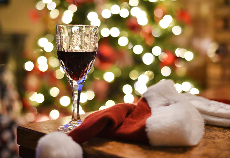 Glass of wine on a table in front of a Christmas tree.