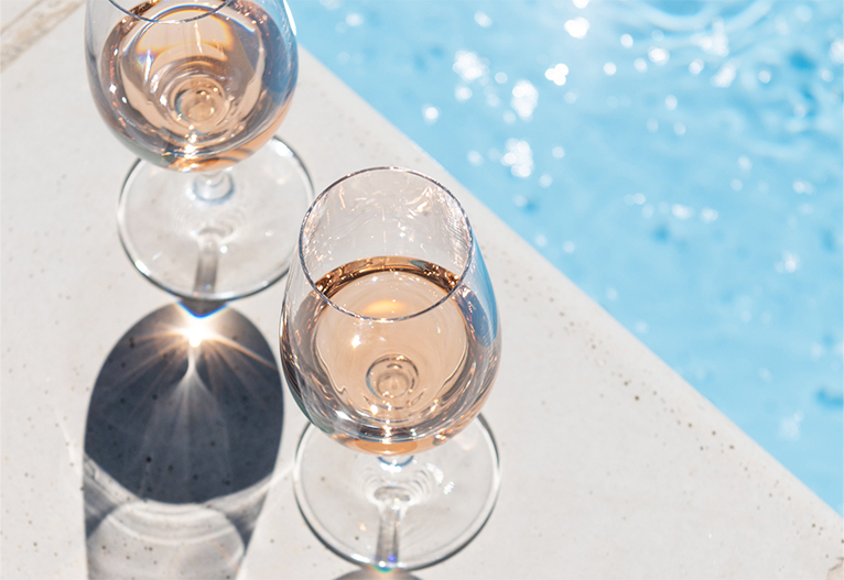 Glasses of wine next to a pool.