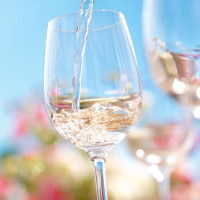 Wine being poured into a glass outdoors.