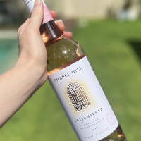 Person holding a bottle of Chapel Hill Enlightened Rosé.