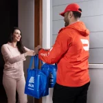 Woman receiving ALDI delivery at her door.