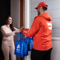 Woman receiving ALDI delivery at her door.