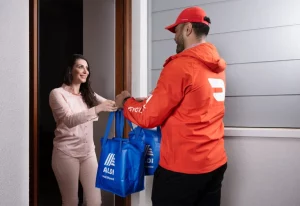 Woman receiving ALDI delivery at her door.
