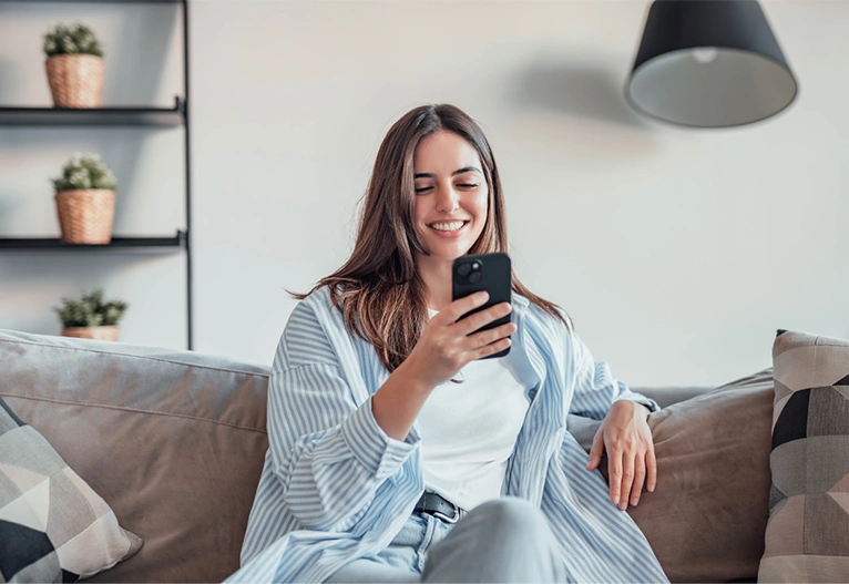 Woman sitting on sofa while using her smartphone.