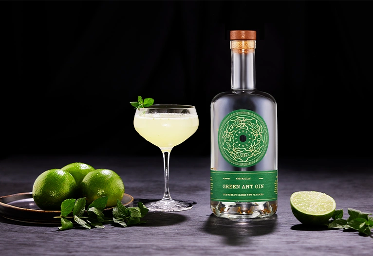 Green Ant Gin bottle next to a cocktail.