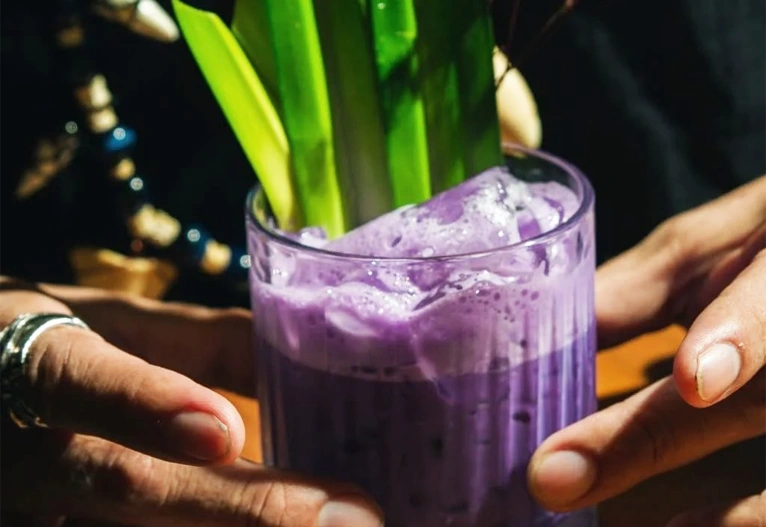 Person holding a mixed drink made with Ube Liqueur.