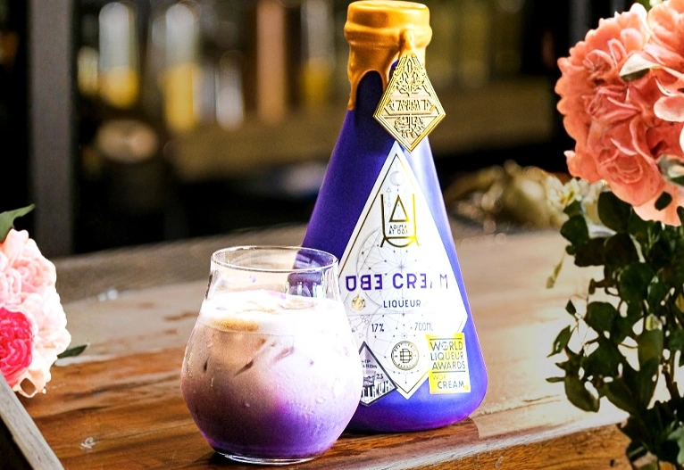Ube Cream Liqueur bottle next to a Purple Russian cocktail.